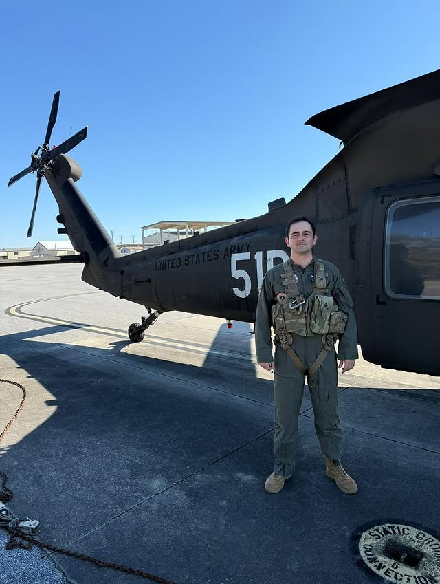 Piloto em frente a helicóptero militar no aeroporto.