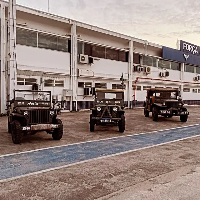Jipes militares antigos em frente a prédio.