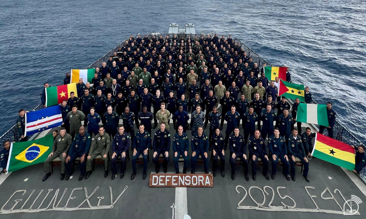 Tripulação militar e bandeiras em navio no mar.