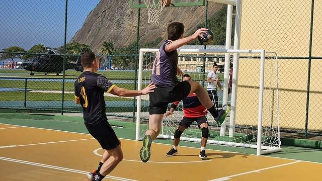 Jogadores de handebol em ação durante partida ao ar livre.