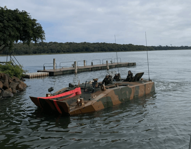 Veículo militar anfíbio no lago próximo a doca.